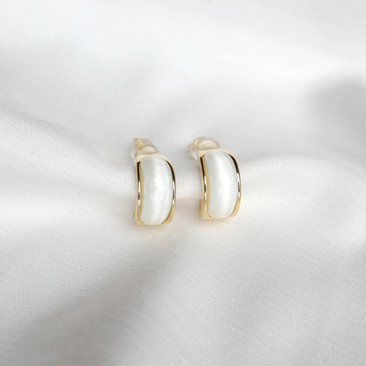 QuinShine Aurelian white earrings with gold trim on white fabric background