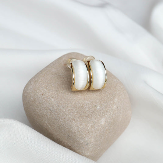 QuinShine Aurelian white earrings with gold trim displayed on a smooth beige stone