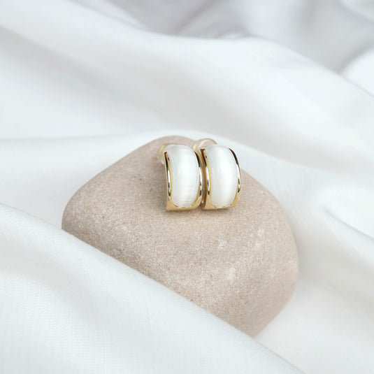 QuinShine Aurelian white earrings with gold trim displayed on a smooth beige stone with white fabric background