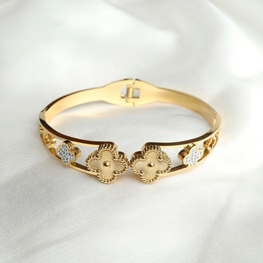 QuinShine gold clover charm bracelet with intricate designs and embedded crystals on a white fabric background