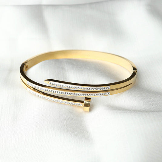 QuinShine gold nail bracelet with crystal detailing on white fabric background