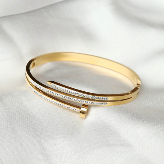 QuinShine elegant gold nail bracelet with embedded crystals on a white fabric background
