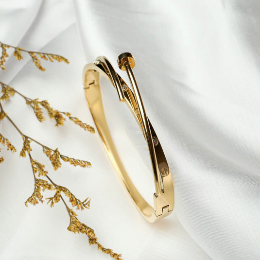 QuinShine sleek sculptural bracelet in gold-tone with unique overlapping design on white fabric