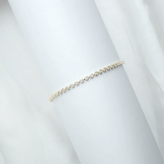 QuinShine luxury gold tennis bracelet with sparkling stones displayed on white cylindrical stand