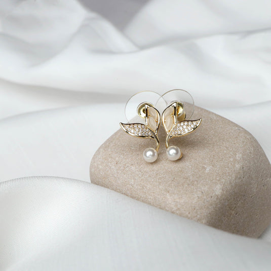 QuinShine vine design earrings gold with leaf shapes, rhinestones, and pearl accents on a smooth stone