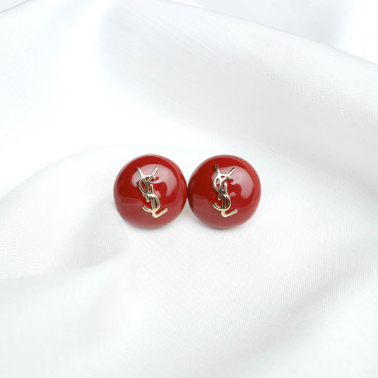 QuinShine red domed earrings for women with gold YSL logo on white fabric background
