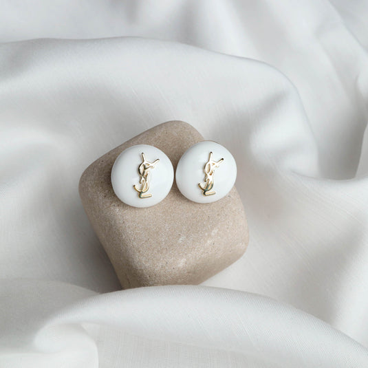 QuinShine white domed stud earrings with elegant gold logo detail on soft white fabric