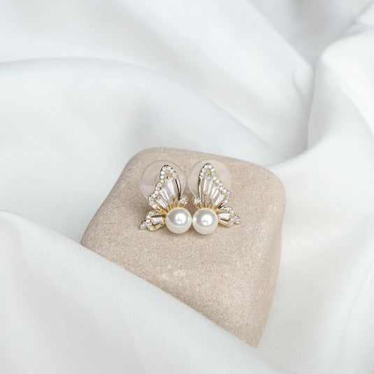 QuinShine butterfly jewelry for women featuring pearl and crystal stud earrings on a beige stone display