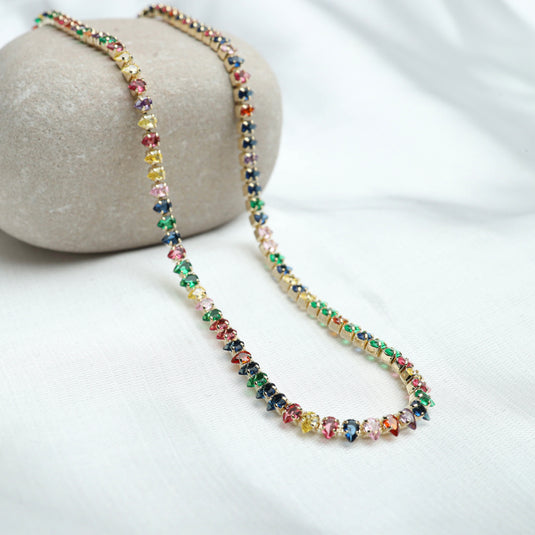 Colorful tennis necklace colorful stones with multicolor gems set in gold chain displayed on neutral background