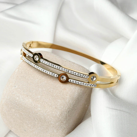 Gold bracelet with sparkling stones featuring QuinShine cosmic jewelry design on beige stone