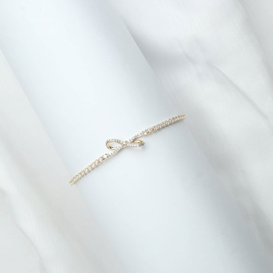 Delicate gold bracelet for women with small sparkling stones and a bow design