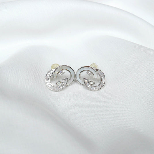 Silver designer link earrings with textured and smooth circular links displayed on white fabric