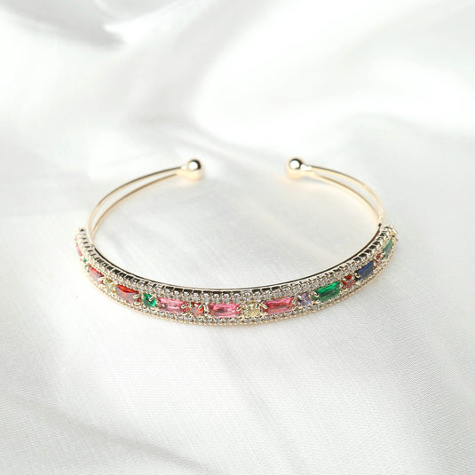 QuinShine elegant cuff bracelet with colorful gemstones set in a gold-tone band on white fabric