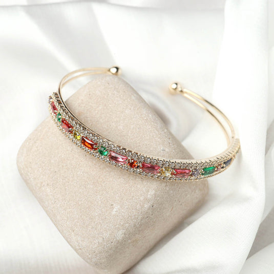 Elegant cuff bracelet by QuinShine featuring colorful gemstones set in a gold-tone band