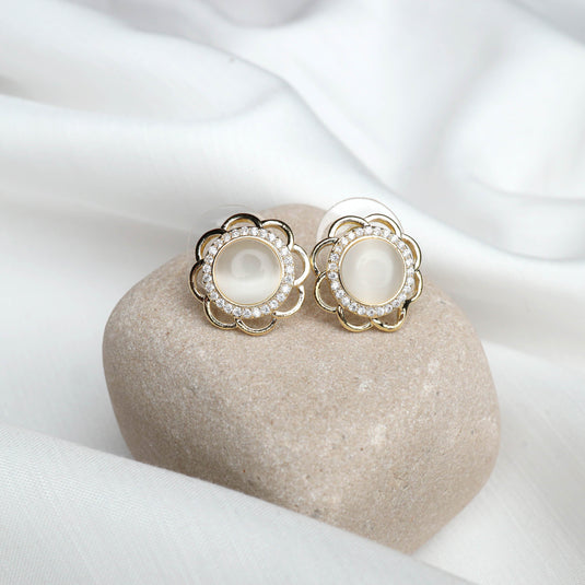 QuinShine Elegant Flower Stud Earrings with gold and crystal design placed on a smooth beige stone