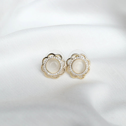 QuinShine elegant flower stud earrings with pearl center and crystal accents on white fabric