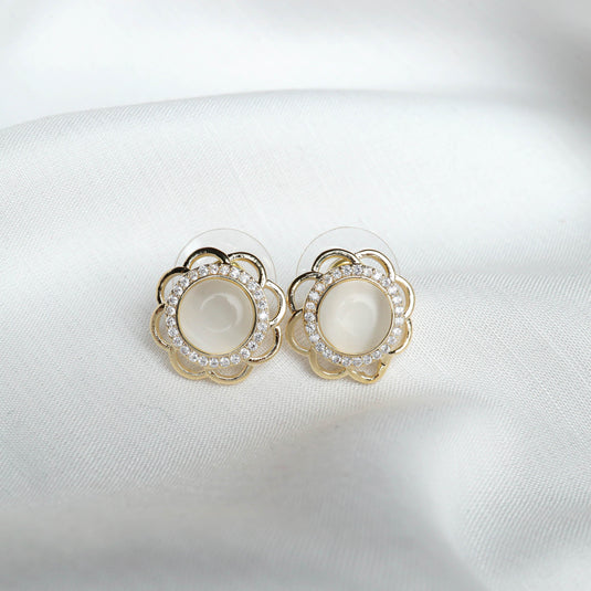 QuinShine elegant flower stud earrings with gold petals and crystal accents on white fabric
