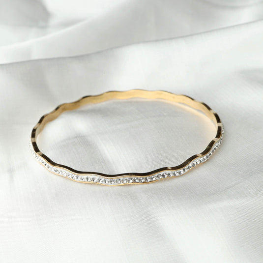 Elegant gold and silver wave bracelet with rhinestone detailing by QuinShine on white fabric background