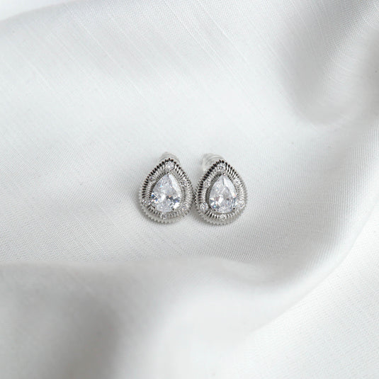 Elegant silver stud earrings with teardrop-shaped clear stones on white fabric background