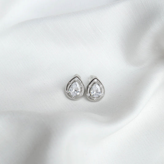 QuinShine elegant silver stud earrings with teardrop-shaped clear stones on white fabric