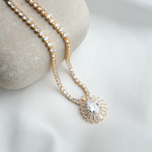Gold chain with clear gemstones and teardrop pendant of the Elysian Sparkle Necklace by QuinShine