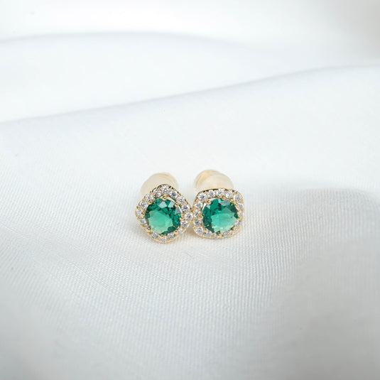 QuinShine emerald crown stud earrings with green gemstones and surrounding clear crystals on white fabric