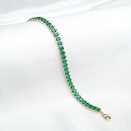 QuinShine elegant emerald green bracelet with gold setting and clasp on white fabric background