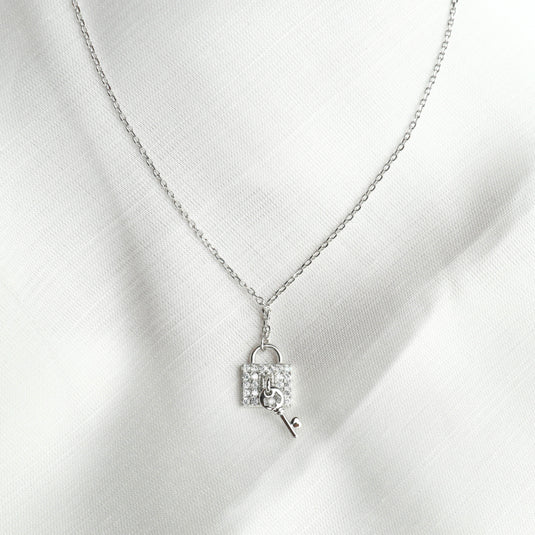 Silver chain fashionable key charm Necklace with a sparkling lock and key pendant on white fabric