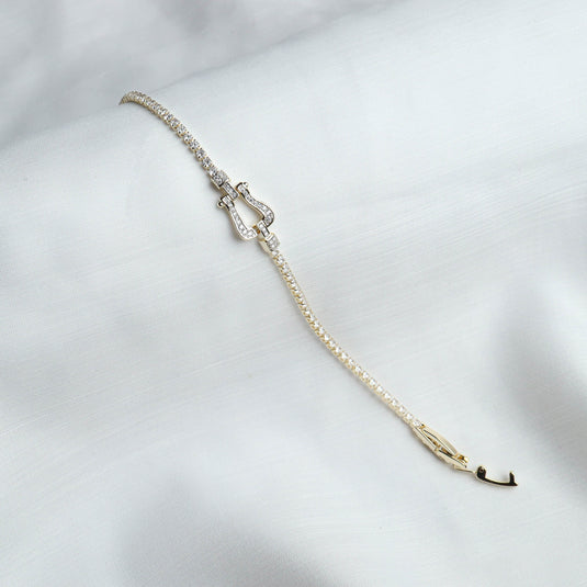 QuinShine delicate gold arc bracelet with sparkling stones on white fabric background