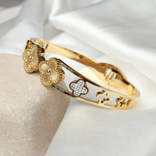 QuinShine gold clover charm bracelet with intricate floral and crystal design on white fabric