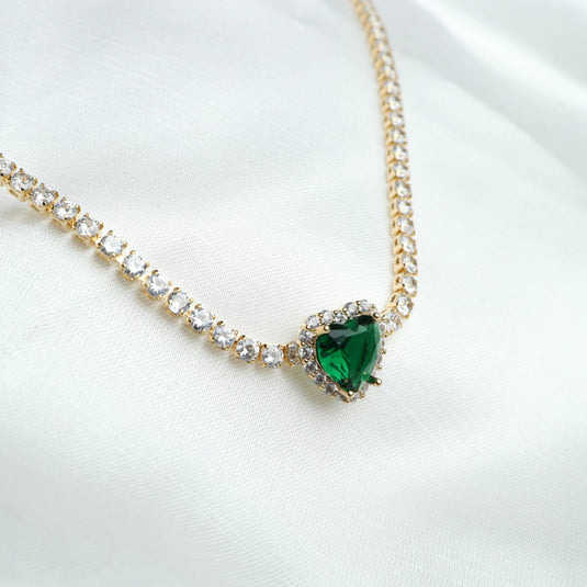 Gold necklace with heart-shaped emerald pendant and surrounding clear stones gold emerald jewelry