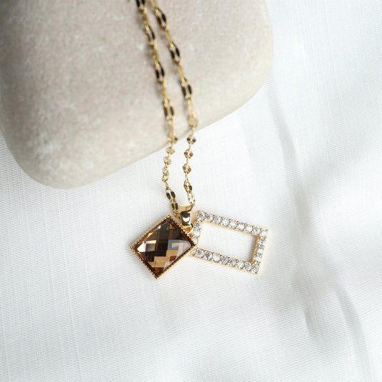 Geometric pendant necklace with a faceted brown stone and a diamond-studded rectangular charm on gold chain