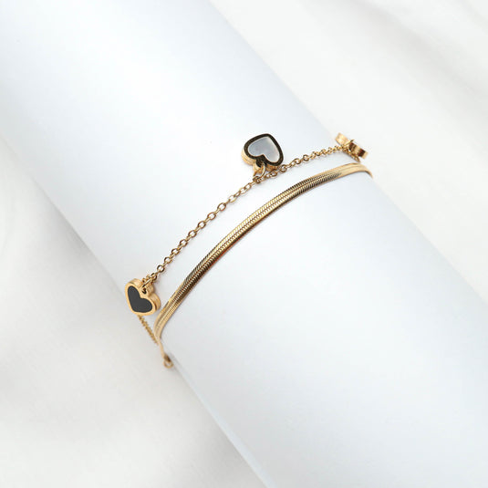 QuinShine delicate gold heart charm bracelet with black enamel hearts on a white display
