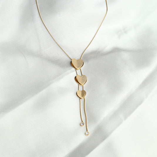 Elegant gold heart lariat necklace with three textured heart pendants and crystal accents