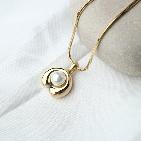 Gold modern pearl pendant necklace with a round pearl center on a delicate chain