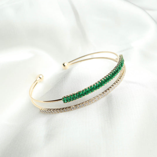 QuinShine gold plated emerald bangle with green emerald stones and elegant design on white fabric