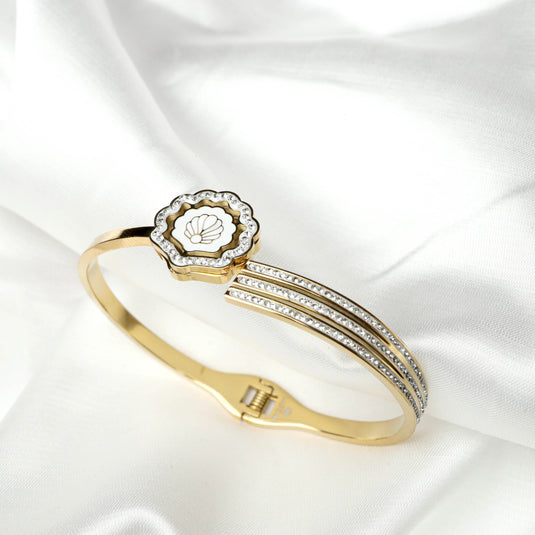 QuinShine elegant gold shell bracelet with sparkling accents on white fabric background