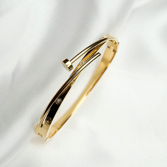 QuinShine gold sleek sculptural bracelet with diamond accents on white fabric background