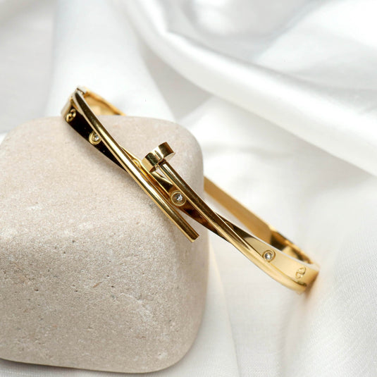 QuinShine gold sleek sculptural bracelet with embedded stones displayed on a stone and white fabric