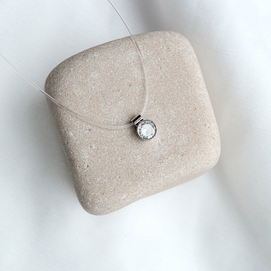 QuinShine gold transparent chain necklace with a clear gemstone pendant displayed on a beige stone