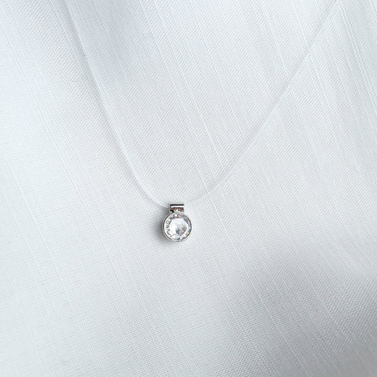 QuinShine gold transparent chain necklace with a round clear crystal pendant on white fabric
