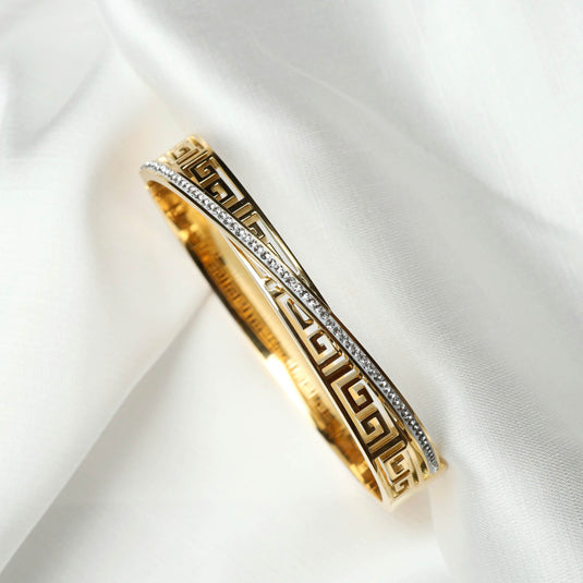 QuinShine Greek Key Bracelet Gold with intricate design and embedded crystals on white fabric