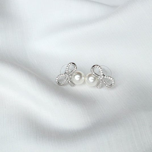 QuinShine delicate loop design earrings with rhinestones and pearl accents on white fabric