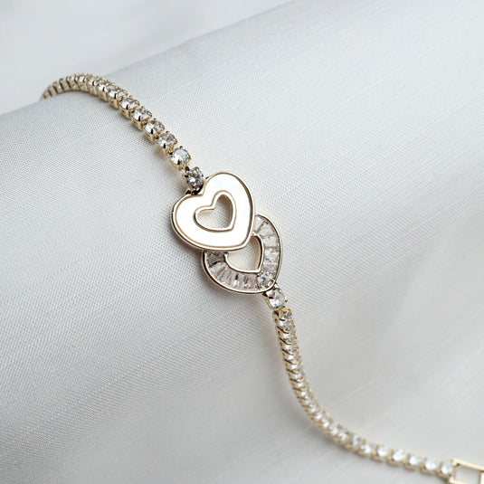 QuinShine love knot tennis bracelet with heart-shaped charms and sparkling stones on a white background