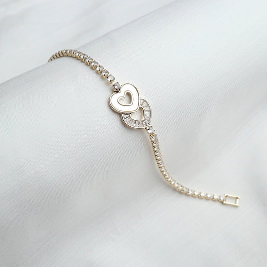 QuinShine love knot tennis bracelet with heart charm and sparkling stones on white fabric