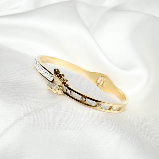 Gold Monarch Glow Bracelet with butterfly design and embedded crystals on white fabric background