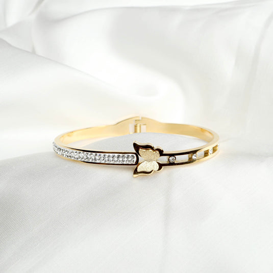 QuinShine Monarch Glow Bracelet in gold with butterfly design and crystal accents on white fabric