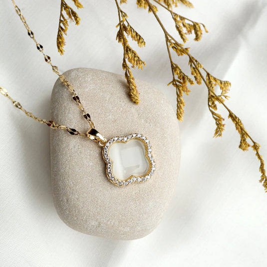 QuinShine Moroccan flower necklace with gold chain and crystal-studded floral pendant on stone background