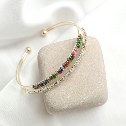 QuinShine multicolor jewelry bracelet with gold finish and sparkling stones on a beige stone background