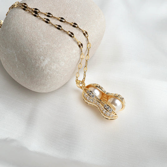 Gold peanut shell locket necklace with pearl and crystal accents on delicate chain